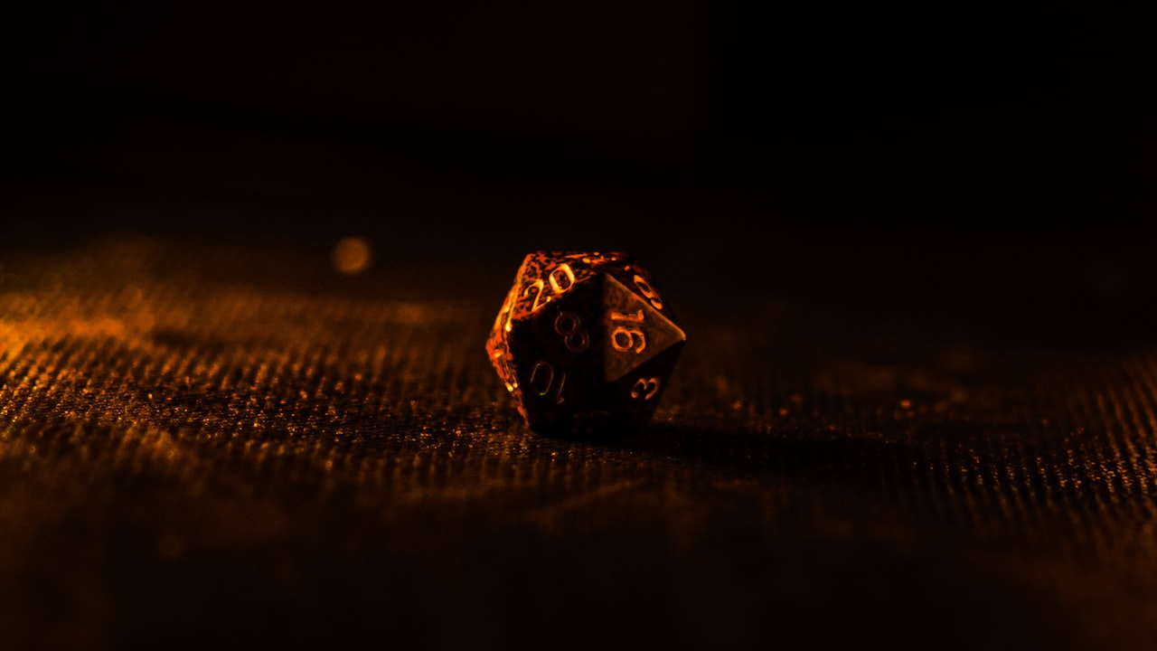 A close-up of polyhedral dice resting on a dark wooden table