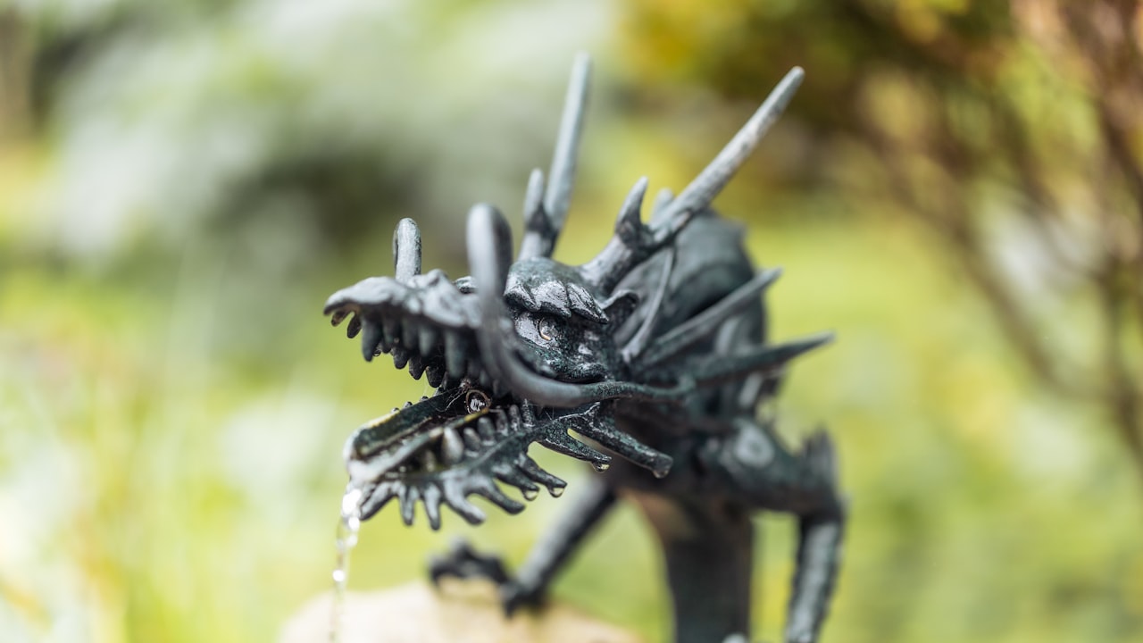 A dark, weathered dragon statue with bared teeth, looming against a stormy green sky